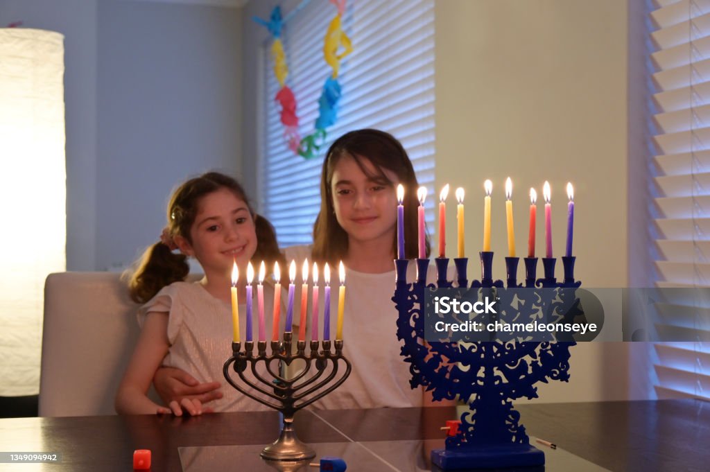 Sisters looking at candelabrum on the eight day of Hanukkah Jewish holiday festival Two sisters looking at candelabrum (hanukkiah) on the eight day of Hanukkah Jewish holiday festival commemorate the rededication of Jerusalem Second Temple in the 2nd century BCE. History Stock Photo