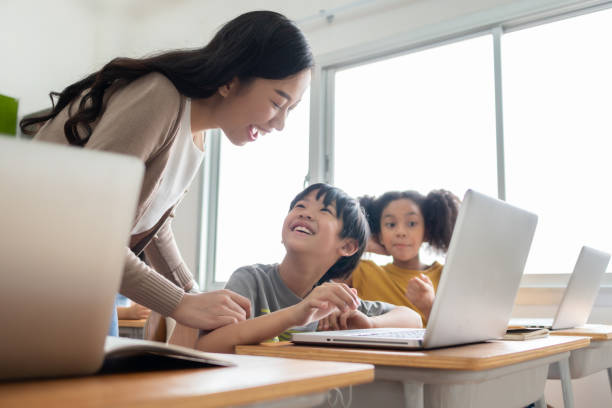 Happy Smiling Asian female teacher is teaching and advice her Asian boy learning on laptop. Happy Smiling Asian female teacher is teaching and advice her Asian boy learning on laptop computer at international primary school. elementary student with teacher stock pictures, royalty-free photos & images