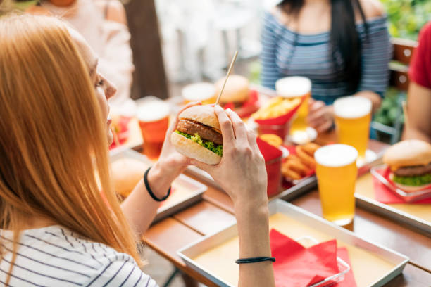 istock Woman with burger having lunch with friends 1349097627