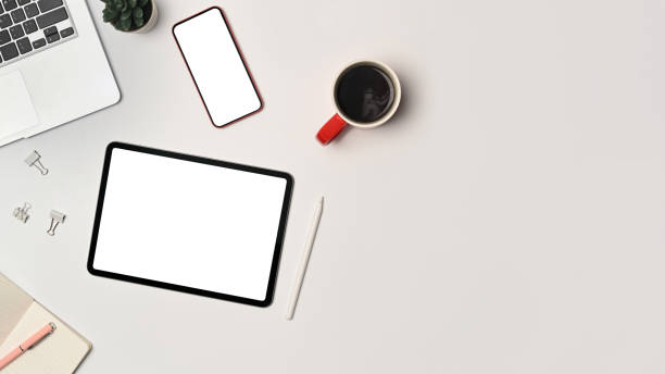 istock Above view digital tablet, smart phone and laptop computer on white office desk. 1349097759