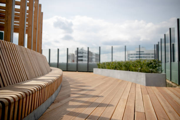 Panorama view of modern rooftop terrace with dark wood deck flooring, plants, brick fence and black garden furniture stock photo