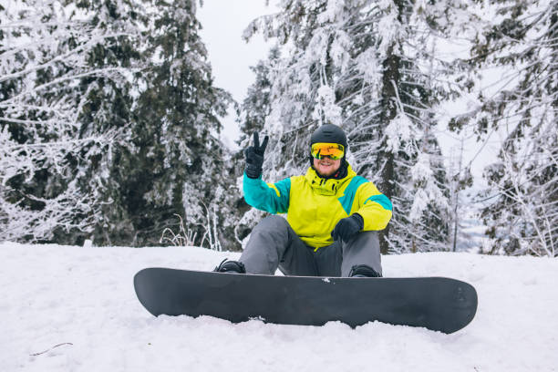 istock man sitting on snowed ground with snowboard 1349111391