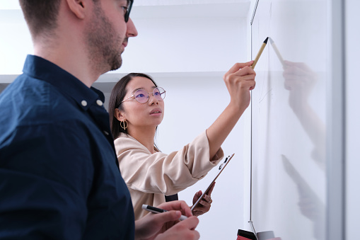 Multiethnic businesspeople develop a business strategy on a whiteboard.