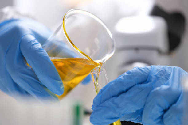 istock Gloved hands pour liquid biofuel into a flask 1349116351