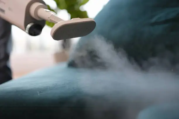 Photo of The vacuum cleaner cleans upholstered furniture with steam