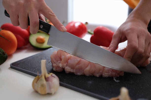 istock Female hands cut meat with a knife, vegetables on the table 1349116653