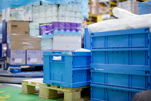 Large stacks of crates and boxes with merchandise on pallets in warehouse