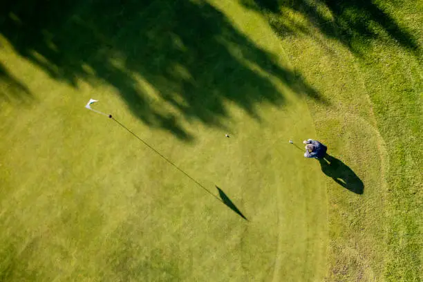 Drone perspective view of a golfer lining up a putt on the green. Shot on location on a golf course on the island of Moen in Denmark. Horizontal format with some copy space.