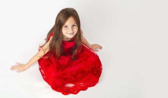 Beautiful child girl in an elegant red dress on a white background. Childhood. Children's fashion. Children holidays. Little Princess. Copy space