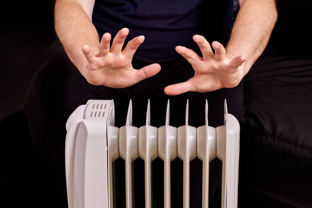 istock Electric heater with man who is warming his hands near. 1349130222