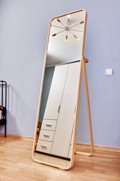 Growth mirror stands in bedroom on laminate floor.