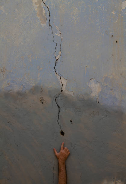 istock Hand pointing a hole of crack in old wall 1349131367