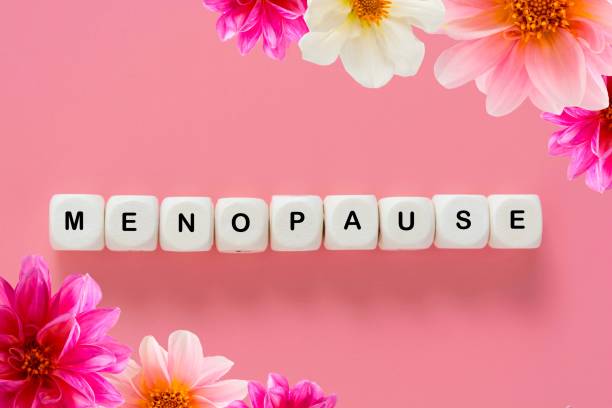 更年期語抽象テキスト、ダリアの花を持つ木製のブロック、��ピンクの背景の上 - menopause ストックフォトと画像