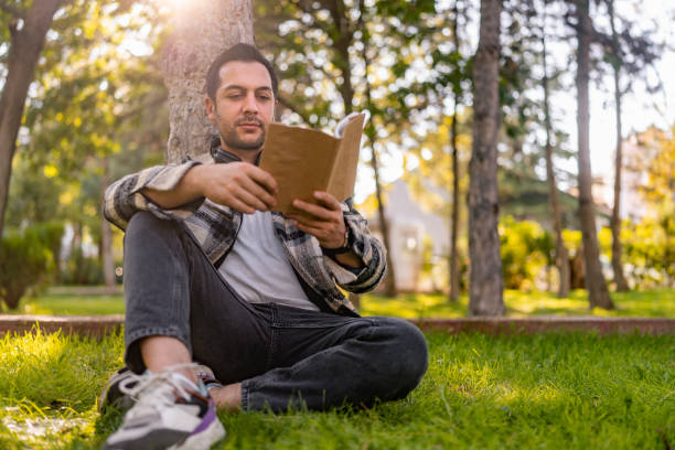 istock Handsome man relaxing and reading book in nature 1349132002