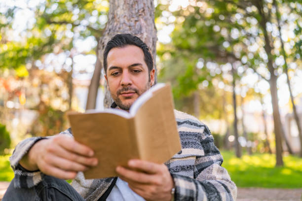 istock Handsome man relaxing and reading book in nature 1349133414