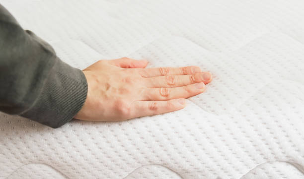 istock Hand touching orthopedic mattress on bed. 1349133527