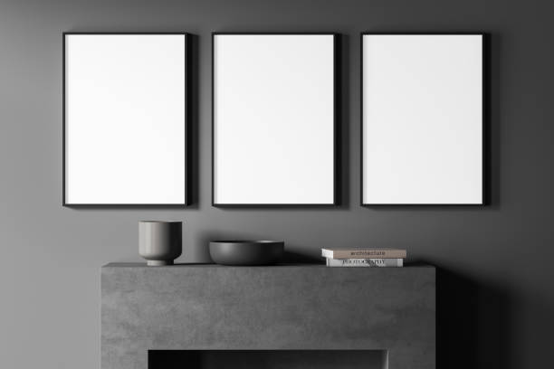 istock Three empty canvases on dark grey living room wall with fireplace beneath 1349138243