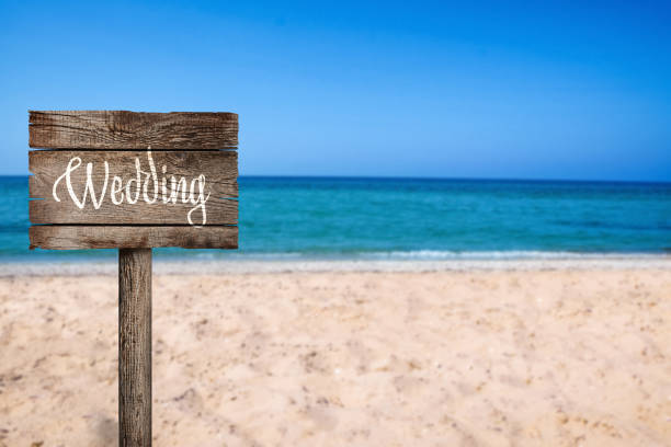 istock Wooden plaque with inscription Wedding on sandy beach, space for text 1349139080