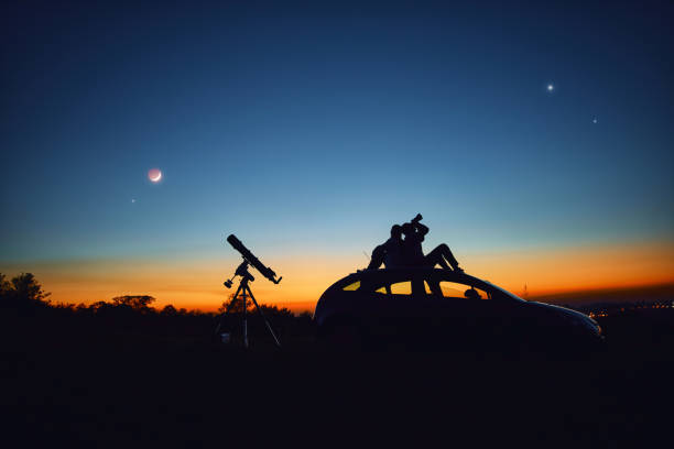 istock Couple stargazing together with a astronomical telescope. 1349139619