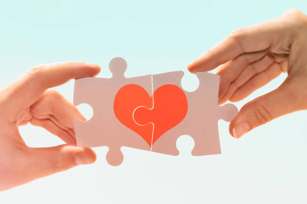 Compatibility between man and woman. A man and a woman connect pieces of a puzzle with a picture of a heart. Compatibility between man and woman. things that go together stock pictures, royalty-free photos & images