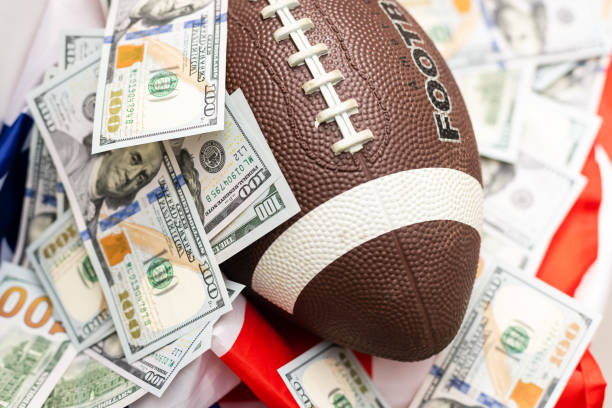 istock rugby ball and dollars on american flag 1349142541