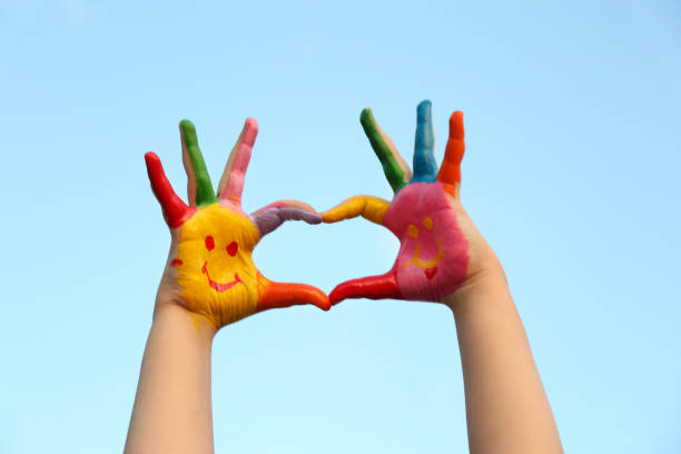 istock Kid with smiling face drawn on palms against blue sky, closeup 1349143440