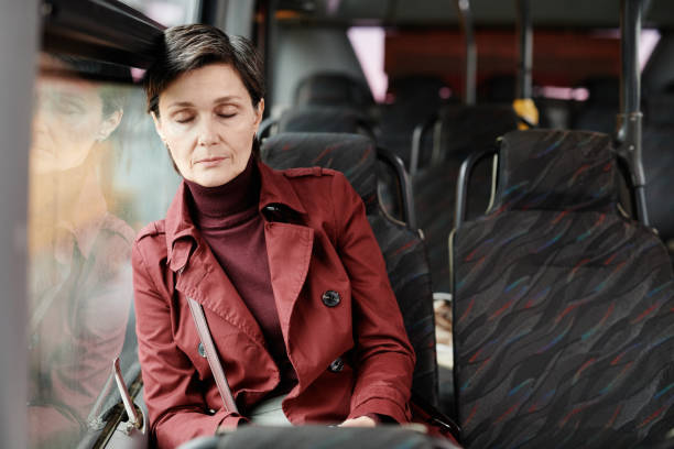 Woman Sleeping on Bus Portrait of elegant mature woman sleeping on bus while traveling by public transport in city, copy space tired after work stock pictures, royalty-free photos & images