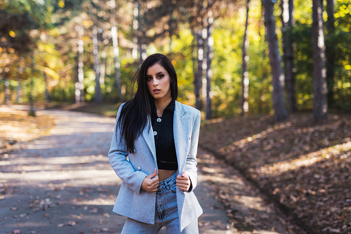Handsome young businesswoman walking in autumn park