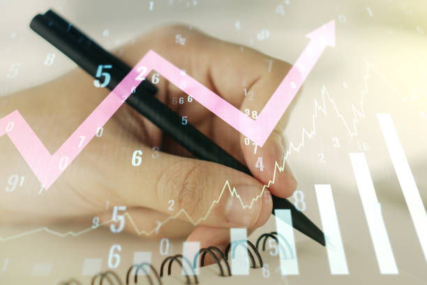istock Multi exposure of abstract creative financial graph with upward arrow and man hand writing in notebook on background, forex and investment concept 1349157429