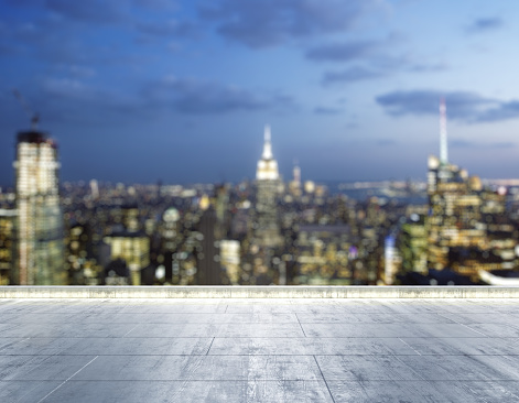 Empty concrete dirty rooftop on the background of a beautiful blurry New York city skyline at night, mock up