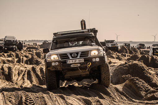 Rockanje, Netherlands -  Sunday October 24th, 2021: Off road 4x4 vehicles driving through man made sand trenches on a public beach on a sunny Sunday morning in the autumn of 2021 in Rockanje, the Netherlands
