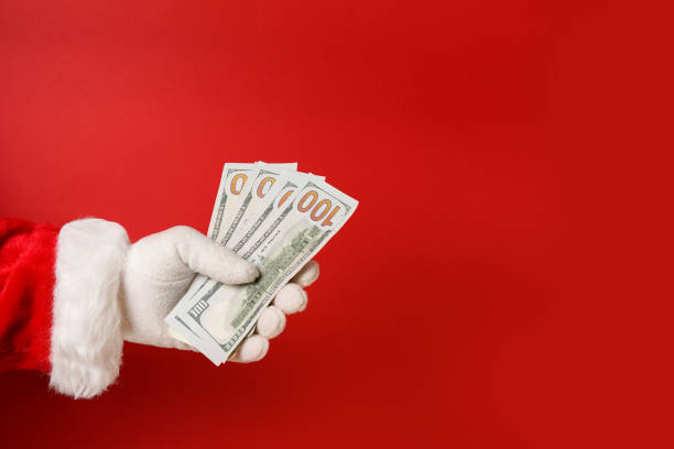 istock Santa Claus hand holding money on red background, copy space 1349158056