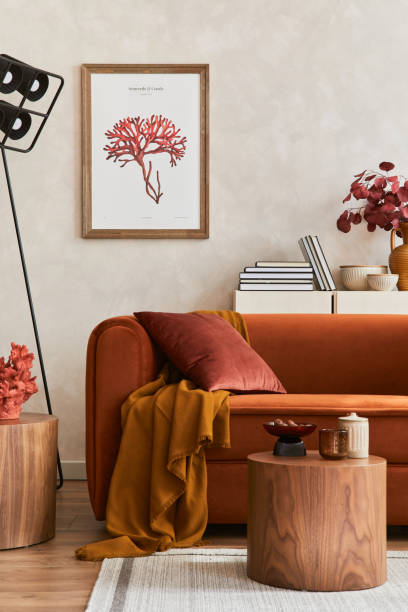 istock Creative composition of stylish living room interior with mock up poster frame, orange sofa, beige commode, coffee table and stylish personal accessories. Artistic space. Template. 1349162516