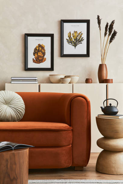 Creative composition of stylish living room interior with two mock up poster frames, orange sofa, beige commode, coffee table and stylish personal accessories. Artistic space. Template. stock photo