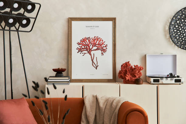 istock Creative composition of stylish living room interior with mock up poster frame, orange sofa, beige commode, coffee table and stylish personal accessories. Artistic space. Template. 1349162523