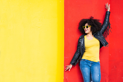 Smiling american-african woman standing on a colored background. Bold colour
