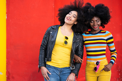 Cheerful afro women standing together and smiling on colorful backgraund.Bold colour