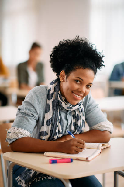 istock Happy black woman writing in notebook while having lecture at university classroom. 1349166998