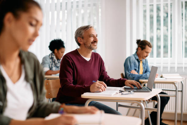istock Happy mature man using laptop and taking notes during lecture in the classroom. 1349167547