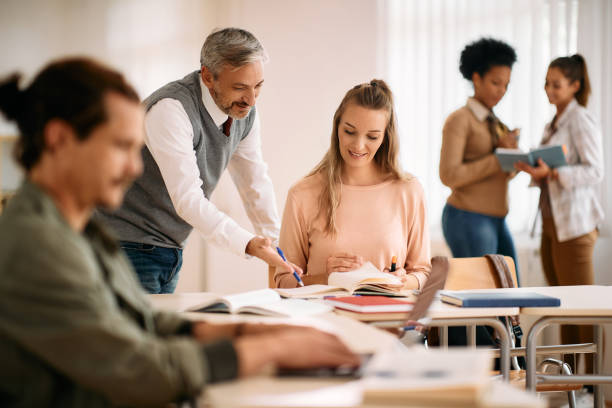 istock Happy woman studying with teacher's assistance during a class at lecture hall. 1349168478