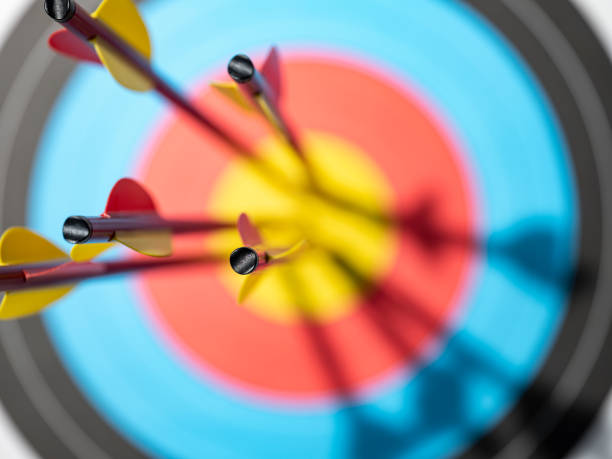 Archery arrows in the bull's-eye of a sports target. Five arrows in the bull's-eye of an archery target.  Concept image of being on target, strategy, aim, accomplishment, aiming for the bull's eye, etc. archery stock pictures, royalty-free photos & images