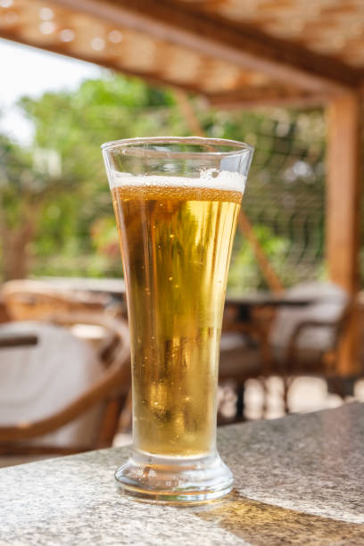 istock Vertical image of a glass with light beer on the table in a summer cafe 1349175789
