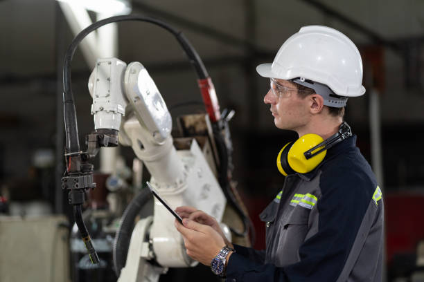 trabalhador de engenheiro masculino usando tablet digital para controlar máquina de braço robótico automático na fábrica. técnico homem trabalhador manutenção mão robótica automática em fábrica inteligente com tablet - cnc vehicle part quality control industry - fotografias e filmes do acervo