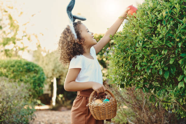 イースターエッグを見つけるために宝探しに行く小さな女の子のショット - easter egg hunt ストックフォトと画像