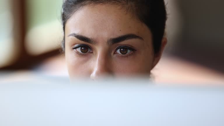 Closeup face focused young indian female looking on computer screen