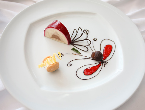 Painted dessert on a special plate. Butterfly and some flowers.