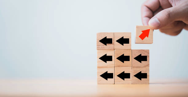 istock Hand holding red arrow which print screen on wooden cube block and move from opposite direction from black arrow , Technology and business disruption after new normal concept. 1349187240