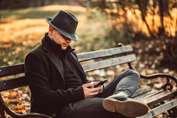 Young stylish man sitting on roof and looking at cityscape during date with girlfriend