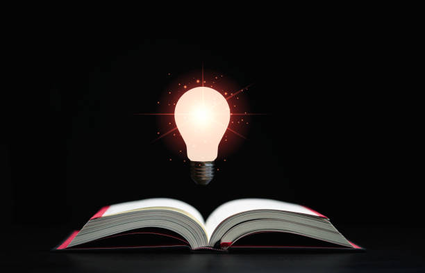 istock Glowing lamp floats above an open book on dark background which is a symbol of study  a knowledge will help solve problem and solution concept. 1349188919