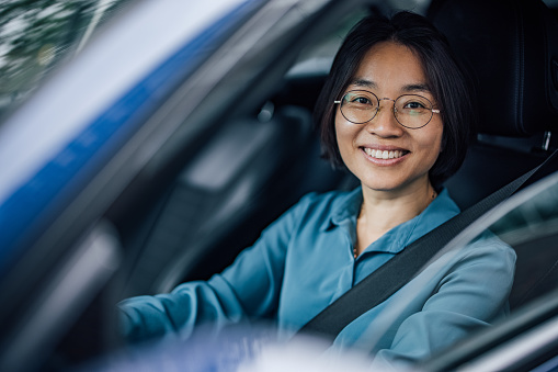 Portrait of a female driver smiling at camera. Commute to work.